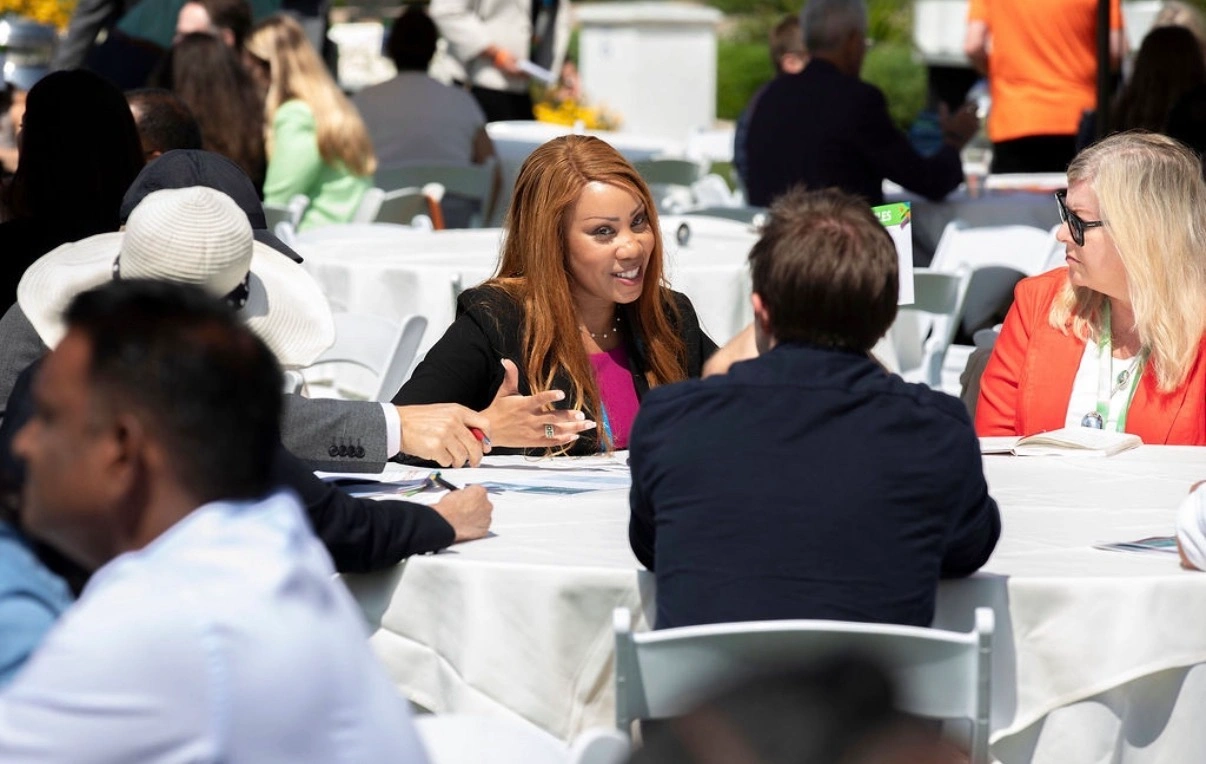 Nicole Van Valen seated at a table in conversation with a small group of leaders during a working session